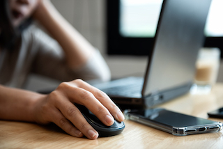 Close up on the hand of a student sitting at a computer holding a mouse